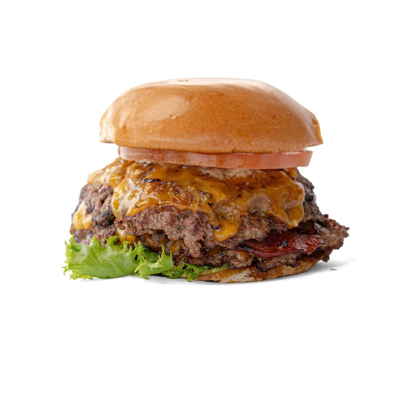 Double cheeseburger with melted cheese, bacon, lettuce, and tomato on a bun.