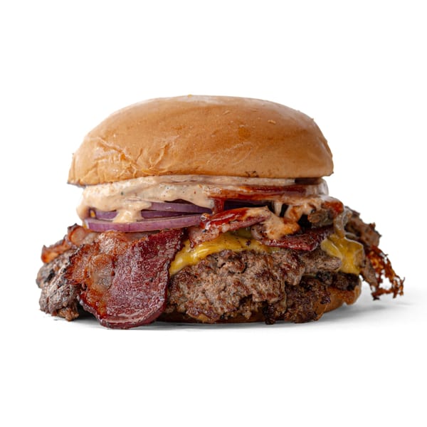 A large burger with two patties, melted cheese, bacon, red onion, and sauce on a bun.