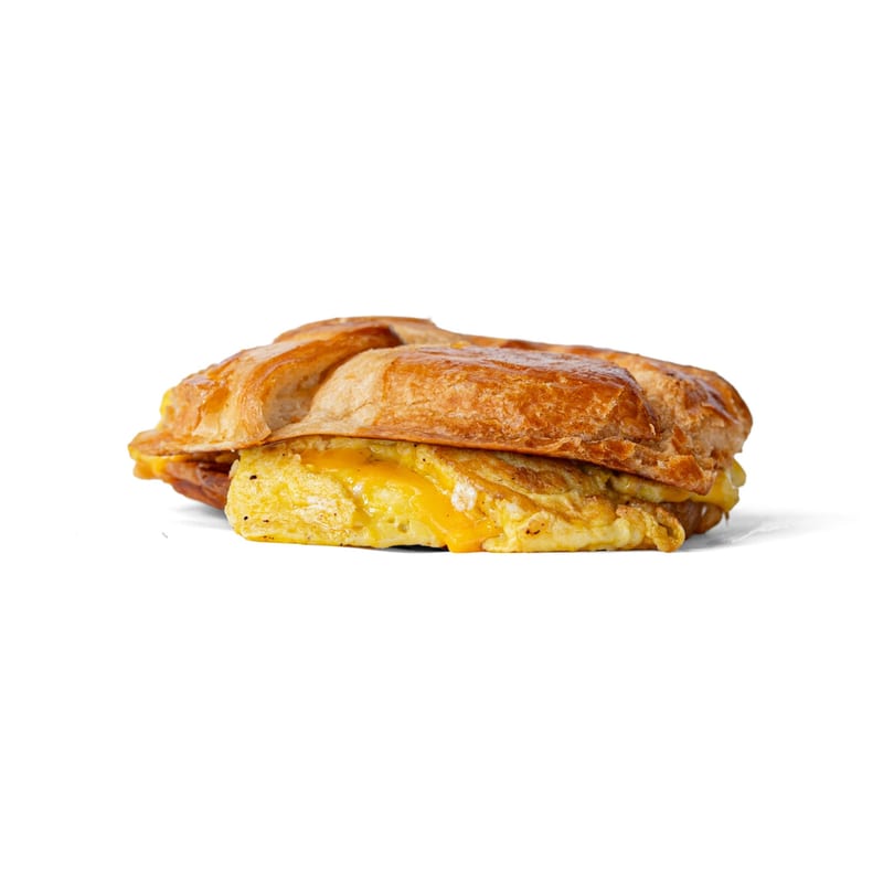 Golden croissant sandwich filled with fluffy scrambled eggs and melted yellow cheese.