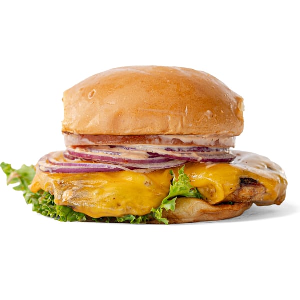 A chicken burger with melted cheese, red onions, lettuce, and sauce on a bun.