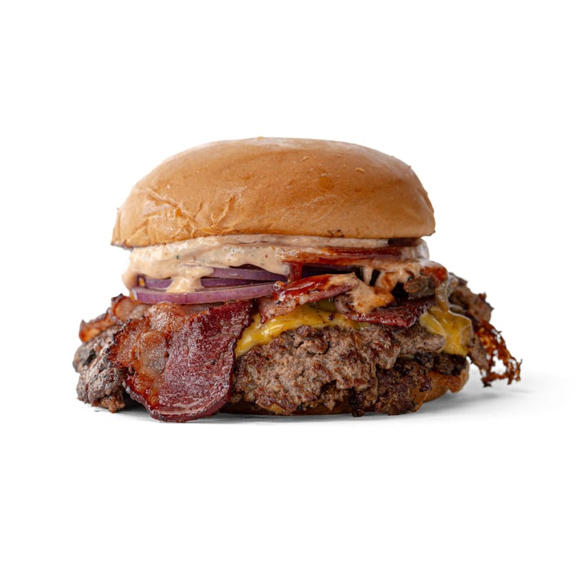 A large, juicy burger with two patties, melted cheese, bacon, red onion, and sauce.