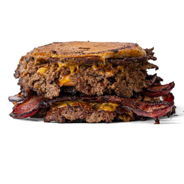 A large, greasy burger with multiple patties, melted cheese, and bacon, on a white background.